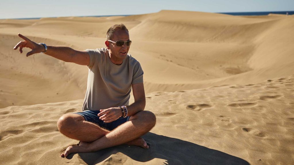 Patrick Hewer der Inspirator im Sand sitzend